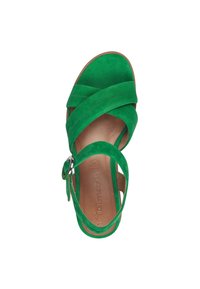Sandalo verde in suede con cinturini incrociati, fibbia alla caviglia e soletta liscia color sabbia con nome del marchio impresso. Suola piatta, design open-toe.