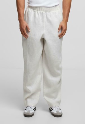 Pantalon en mélange de lin, beige clair, avec une taille élastique et des poches latérales, présentant une coupe droite et ample. Assorti à des chaussures de sport.