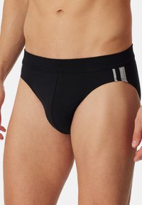 Sorte bomuldsboxershorts med en tætsiddende design, der har en blød talje og grå accentstriber på begge sider. Glat tekstur og minimalistisk stil.