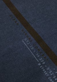 Tissu bleu foncé avec une finition texturée, arborant des textes blancs et bruns, y compris "CONCEPT VISUEL CLAIR" et d'autres détails numériques.