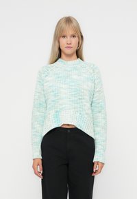 Heklet-genser i lyseblå og hvit. Har en teksturert strikk, ribbestrikket kant og en cropped, boksformet silhuett.
