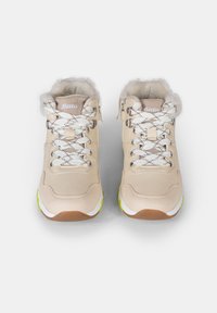 Zapatillas altas beige con cordones blancos y acentos texturizados, que cuentan con un interior acolchado y una suela con tonos verdes. Logo en la lengüeta.