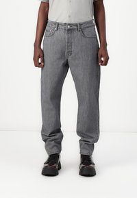 Grå denimjeans med en avslappet passform, fem lommer og knappelukking. Stoffet har en subtil tekstur og en lett falmet finish.