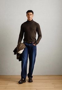 Rjav pulover s turtleneck ovratnikom, modri kavbojki, rjav pas, rjave čevlje in temen plašč, obešen čez eno ramo. Enostavna, oprijeta zasnova.
