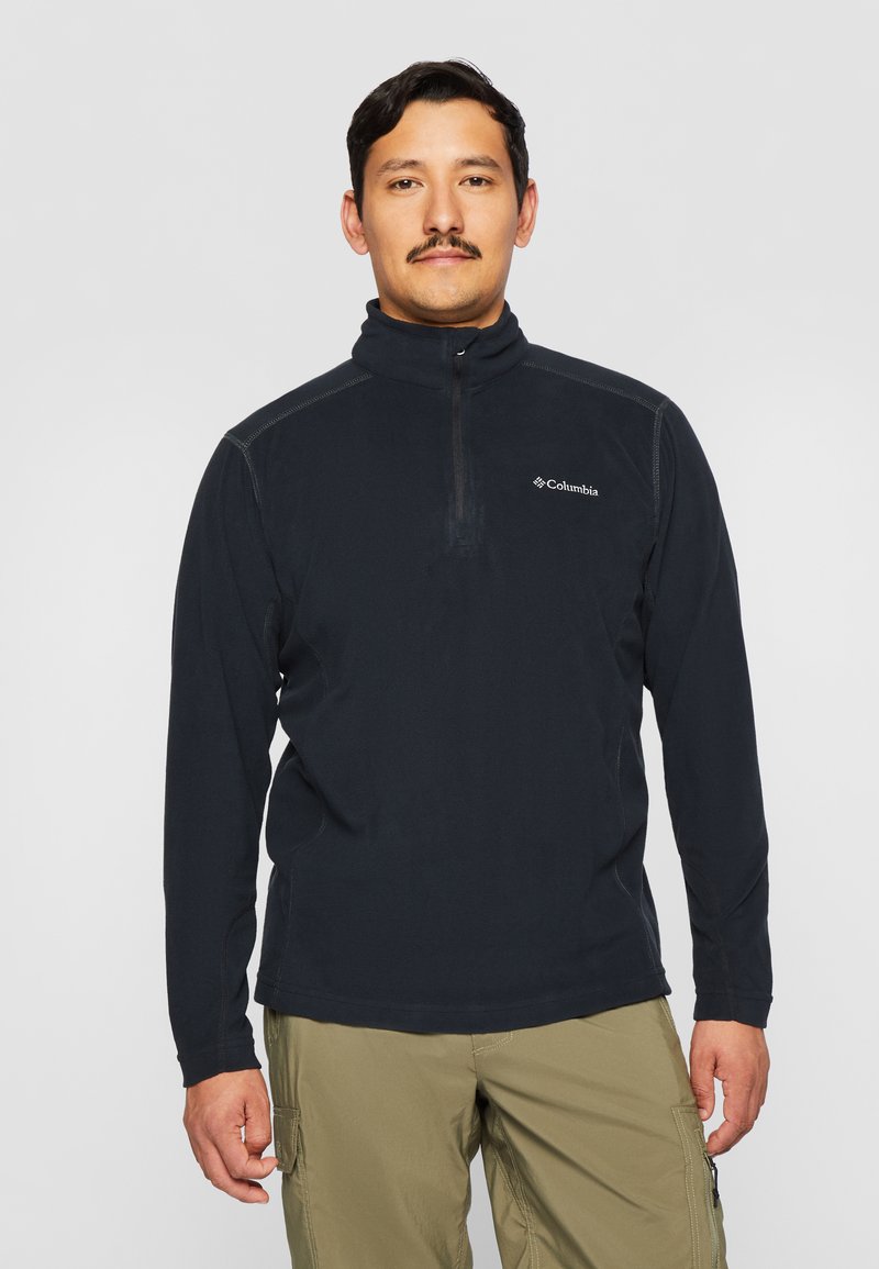 Pull en polaire noir avec une fermeture éclair quart, présentant un col haut et des coutures contrastées. Logo Columbia sur la poitrine gauche.