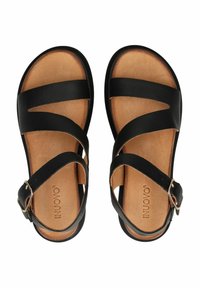 Czarne skórzane sandały z krzyżującymi się paskami, brązowe skórzane wkładki i metalowy akcent z klamrą. Płaska podeszwa o minimalistycznym designie.