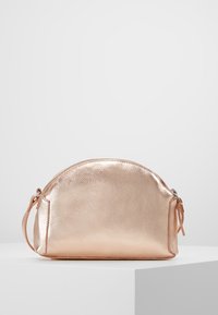 Metaliczna różowo-złota okrągła torba na drobiazgi z zamkiem błyskawicznym, fakturowana powierzchnia i boczny pasek. Gładkie wykończenie i minimalistyczny design.