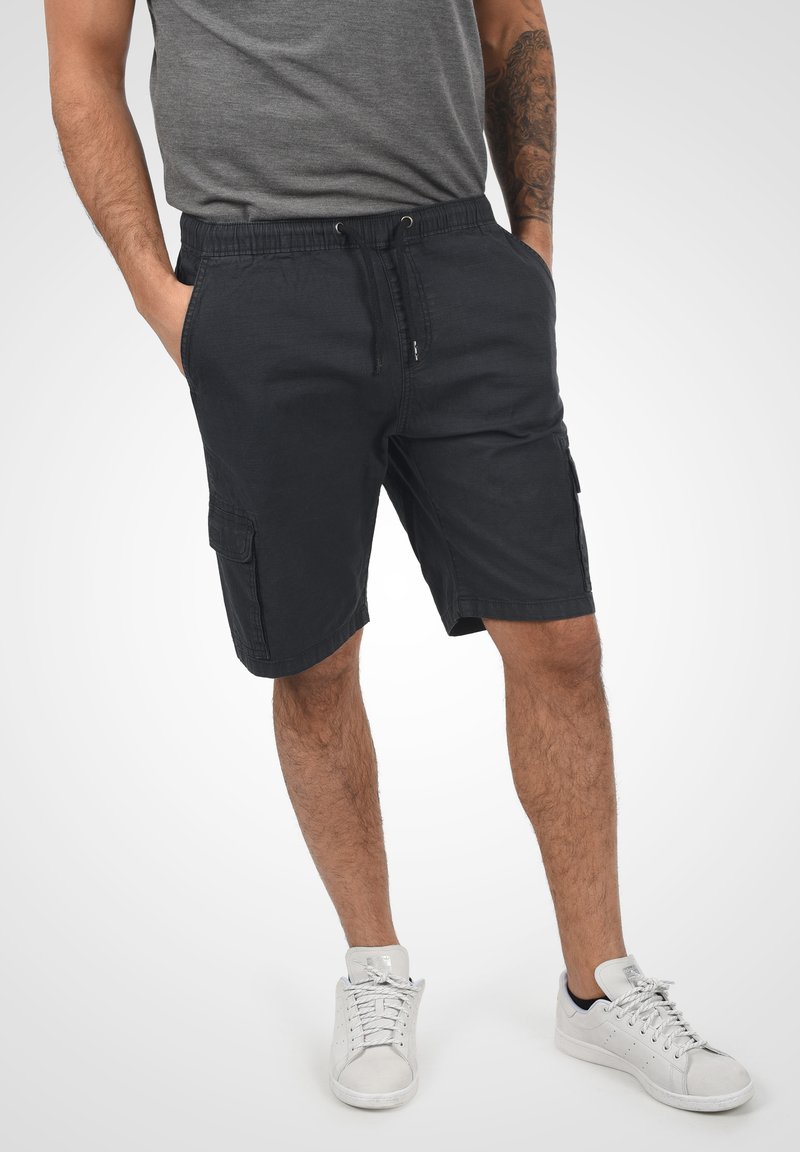 Donkergrijze cargoshorts met een elastische tailleband en trekkoord, voorzien van zijzakken en een casual pasvorm. G gedragen met witte sneakers.
