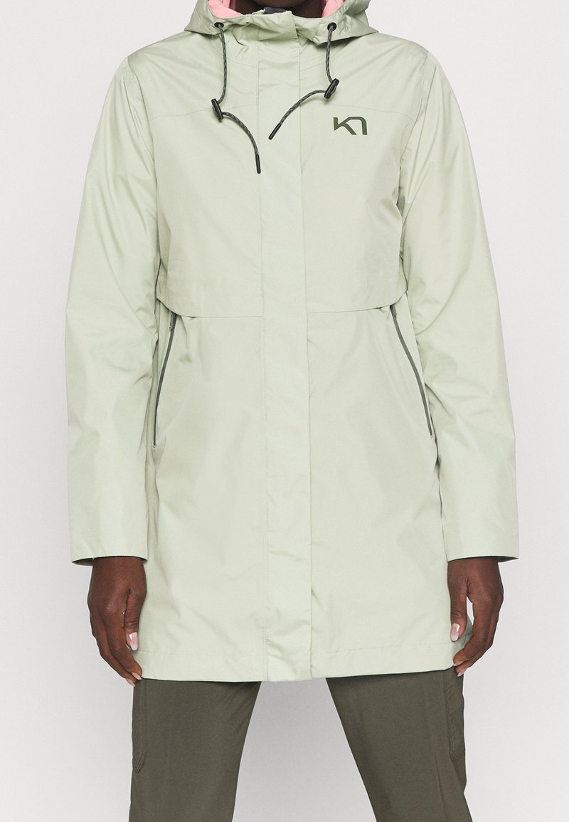 Ljusgrön vattentät jacka med huva, dragkedjefickor och rosa inredning. Har en logotyp på bröstet. Långa ärmar.
