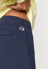 Μπλε ναυτικό παντελόνι jogger από απαλό ύφασμα, με ελαστική μέση, πλαϊνές τσέπες και μικρό κεντημένο λογότυπο.