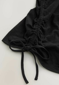 Must mustriga kangas, millel on kogutud külgõmblus ja nöördetail. Tekstuur tundub pehme ja veidi veniv, sujuva langevusega.