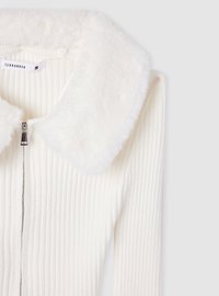Biały żeberkowany kardigan z miękkim futrzanym kołnierzem, z zapięciem na zamek i długimi rękawami. Materiał ma subtelną teksturę i połysk.