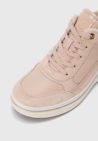 Baskets rose clair combinant cuir lisse et daim, avec des lacets ton sur ton, des œillets dorés, et une semelle blanche agrémentée d'une touche dorée.