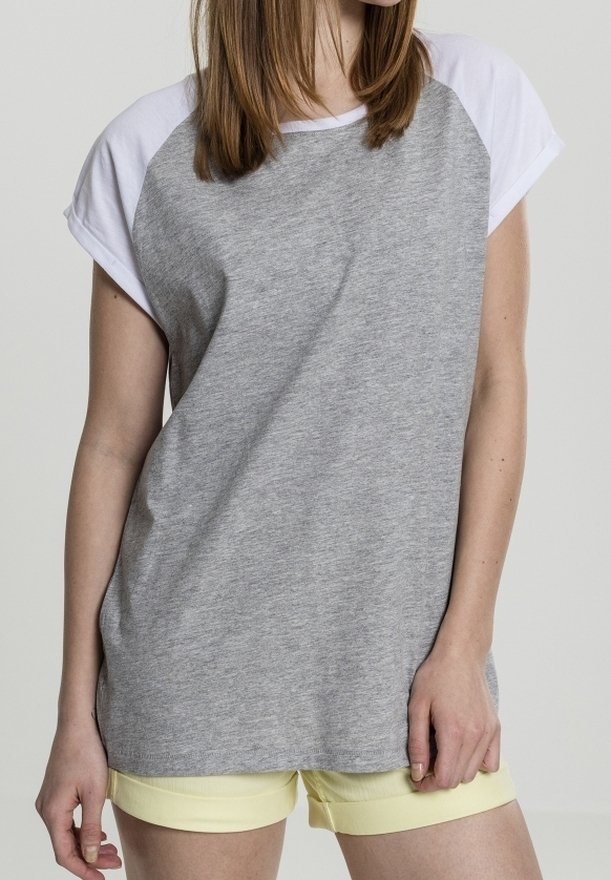 Camiseta gris de manga corta con mangas raglán blancas, hecha de un tejido suave. Presenta un corte relajado y un escote redondeado, combinada con pantalones cortos amarillos.
