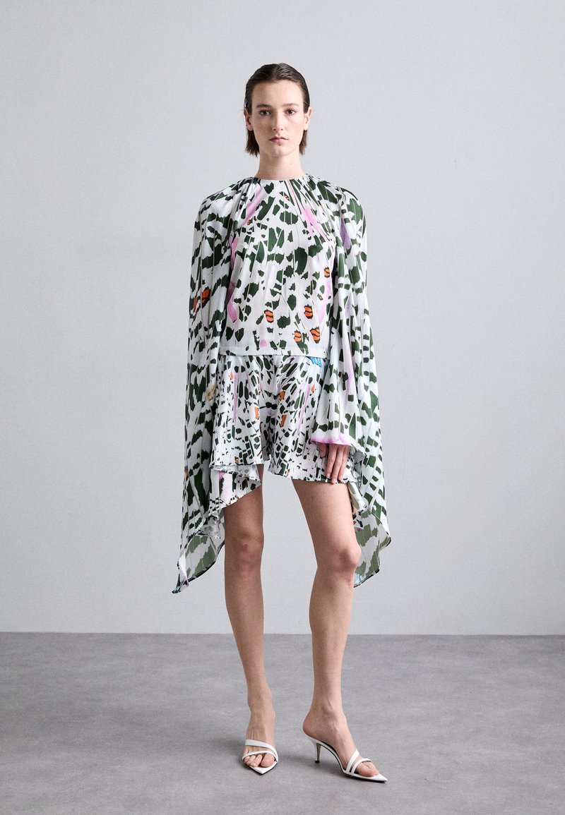 Kurzes Kleid mit tailliertem Oberteil und weiterem Rock. Mit einem grünen, rosa und orangefarbenen Blumenmuster. Durchsichtige Cape-Ärmel aus einem leichten Stoff.