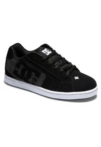 Black sneaker with a textured black and gray upper, featuring a white rubber sole and prominent logo on the side and top. Laces are black.