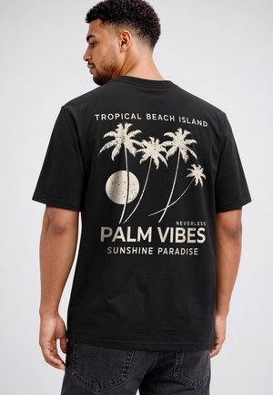 Man wearing black T-shirt with beige palm trees, sun, and text "Tropical Beach Island," "Neverless Palm Vibes," and "Sunshine Paradise" on back.