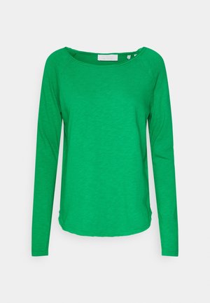 Langarm groen shirt met ronde hals en licht gebogen zoom, afgebeeld op een effen lichtgrijze achtergrond.