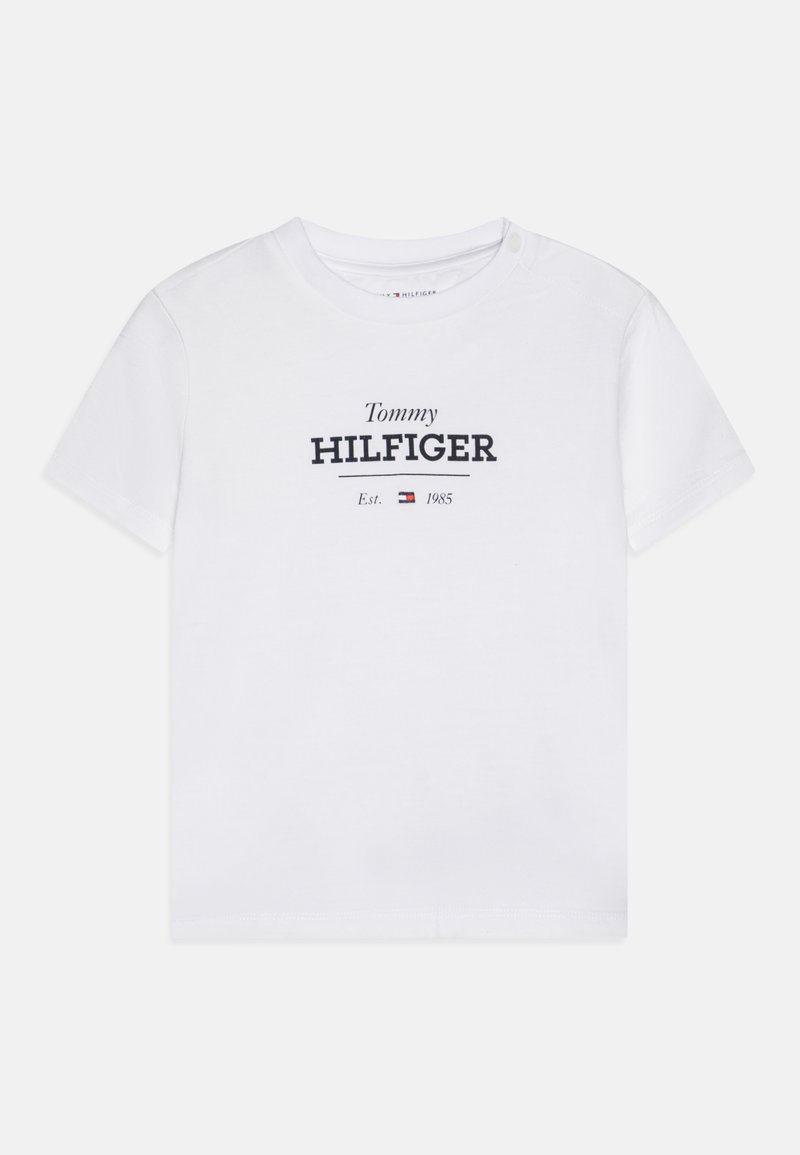 Balta medvilninė marškinėliai trumpomis rankovėmis, su tamsiai mėlynu spaudiniu: "Tommy HILFIGER" ir "Est. 1985" su mažu logotipu.