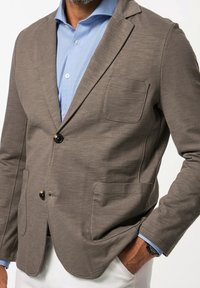 Grauer Blazer mit Struktur, Reverskragen, zwei vorderen Taschen und Ein-Knopf-Verschluss, getragen über einem hellblauen Hemd.