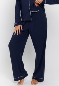 Conjunto de pijama azul marino que incluye una camisa de botones con ribetes blancos y pantalones de corte holgado, confeccionado en un suave tejido acanalado.
