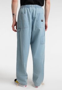 Ljusblå denimbyxor med resårmidja, två stora bakfickor och en liten märkesetikett, avslappnad passform och tapered form.