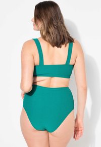 Set di bikini verde a coste con top corto a spalla larga e slip a vita alta. Texture morbida e design aderente.