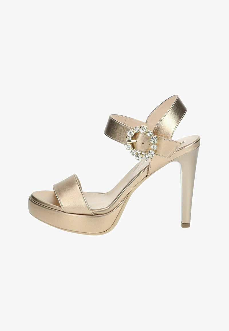 Sandale à talons hauts métalliques dorés avec une large lanière sur les orteils, une lanière autour de la cheville et un détail de boucle en strass circulaire. Caractéristiques d'une semelle plateforme.