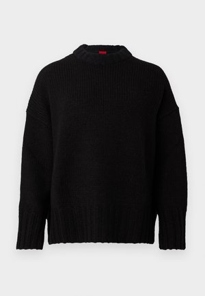 Juodas megztinis su aukštu, raukšlėtu kaklu. Laisvas kirpimas su nuleistais petukais ir raukšlėtomis rankovėmis. Švelni tekstūra ir atsipalaidavęs dizainas.