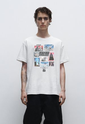 Hvid bomulds t-shirt med et collage af billeder og tekst fra Star Wars: The Empire Strikes Back, rund hals, afslappet pasform, korte ærmer.