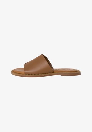 Brune lædersandal med åben tå og bred rem. Har en flad sål med syninger langs kanterne. Enkel, minimalistisk design.