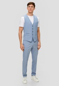 Hellblauer Weste mit glatter Textur, fünf Knöpfen und zwei Fronttaschen, kombiniert mit passenden Hosen und weißen Sneakers.