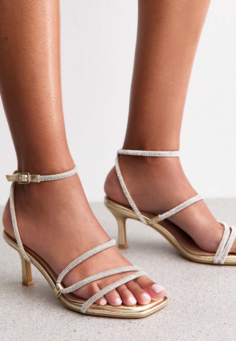 Riemchen-High-Heelsandalen mit goldmetallicfarbener Sohle und klaren Strassakzenten, mit eckiger Zehenpartie und Knöchel-Schnallenverschluss.