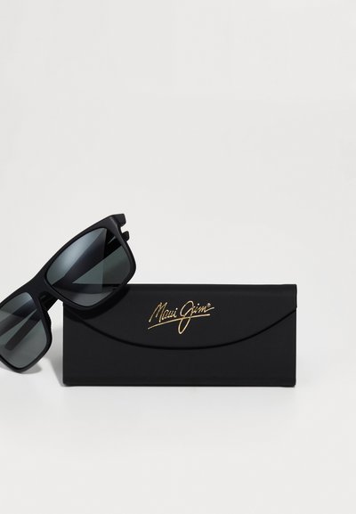 Zwarte Maui Jim zonnebril met grijze lenzen, voorzien van een matte afwerking en een hoekig frameontwerp, geleverd met een slanke zwarte opbergcase.