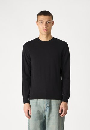 Must karvane sõrmustega sviiter, mis on valmistatud pehmest kangast. Omab pikka varrukat ja ribatud varruka- ja sääreosa äärt. Kombineeritud heledate denim teksadega.