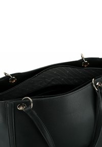 Zwarte leren handtas met zilverkleurige metalen ringen aan de handvatten, open bovenzip met een donkere stofinterieur met een subtiel patroon in de voering.