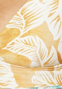 Tecido amarelo e branco com padrão com grandes desenhos de folhas, textura suave e forma ajustada com uma faixa na parte inferior.