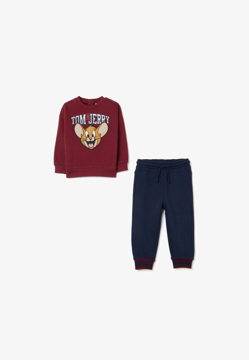 Rode sweatshirt met een Tom en Jerry-afbeelding, gecombineerd met marineblauwe joggingbroek met een elastische tailleband en rode gestreepte manchetten.