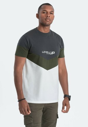 Color-blocked t-shirt featuring dark gray, olive green, and white sections; includes "LEVELUP" text in white. Made of soft cotton fabric.