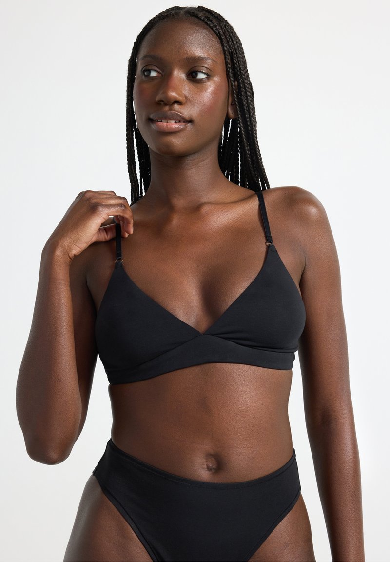 Svart bralette med V-ringning, justerbara band och en slät textur. Matcher med högmidjade svarta bikinitrosor.