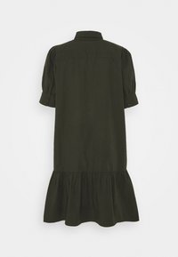 Robe courte à manches courtes vert foncé avec encolure à col et ourlet à volants froncés, vue de dos sur un fond uni.