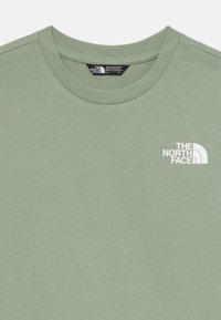 Gaiši zaļš kokvilnas t-krekls ar apaļu kaklu un īsām piedurknēm. Kreisajā krūtī ir balta logo "The North Face".