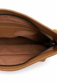 Ruskean nahkalaukun sisäosa, jossa on sileä pinta, vetoketjullinen tasku ja pehmeä kangasvuori. Mukana logoplässi.