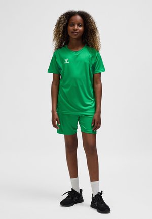 Uniforme de sport vert en matière légère, comprenant un haut à manches courtes et un short, associé à des chaussures de sport noires et des chaussettes blanches.