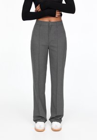 Grijze op maat gemaakte pants met een rechte pijp, voorzien van een soepele textuur, voorplooien en een klassieke tailleband. Gecombineerd met witte sneakers.