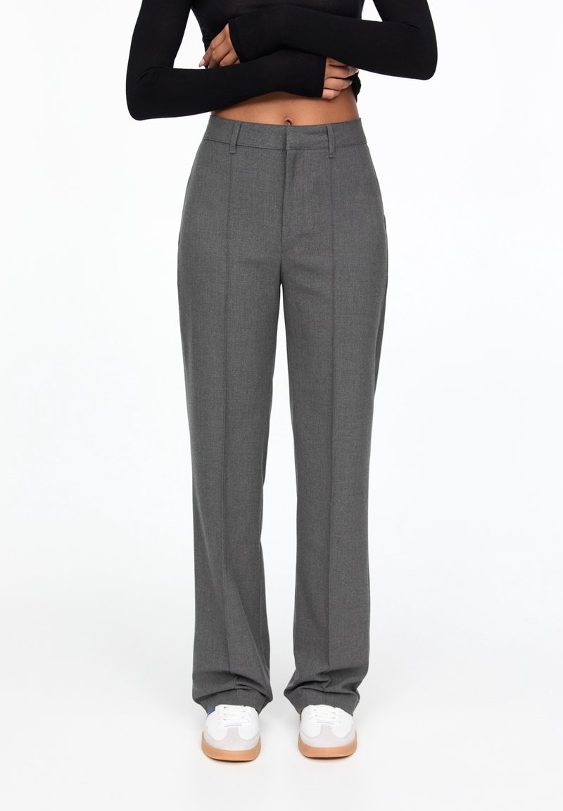 Grijze op maat gemaakte pants met een rechte pijp, voorzien van een soepele textuur, voorplooien en een klassieke tailleband. Gecombineerd met witte sneakers.