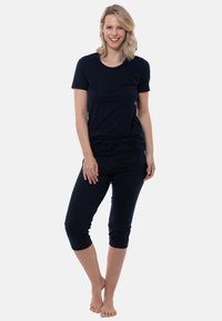 Navy sinisessä löhöasusetissä on lyhythihainen paita ja lyhyet housut, joissa on kiristysnauha. Pehmeä kangas ja rento istuvuus.