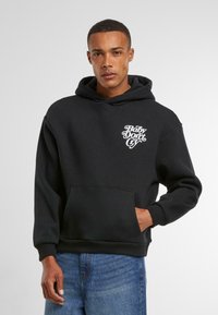 Zwarte katoenen hoodie met een voorzak, voorzien van witte grafische tekst "Baby Don't Cry" op de borst en een capuchon met trekkoord.