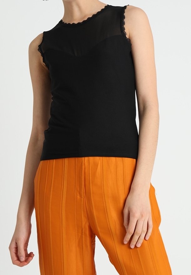 Haut noir sans manches avec un col en dentelle transparente, associé à un pantalon orange taille haute orné de rayures verticales.