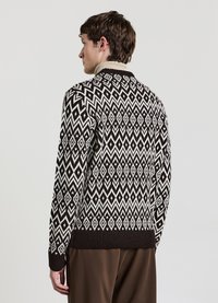 Knit sweater in black and cream featuring a geometric diamond pattern, ribbed cuffs, and high collar. Soft texture with a fitted silhouette.